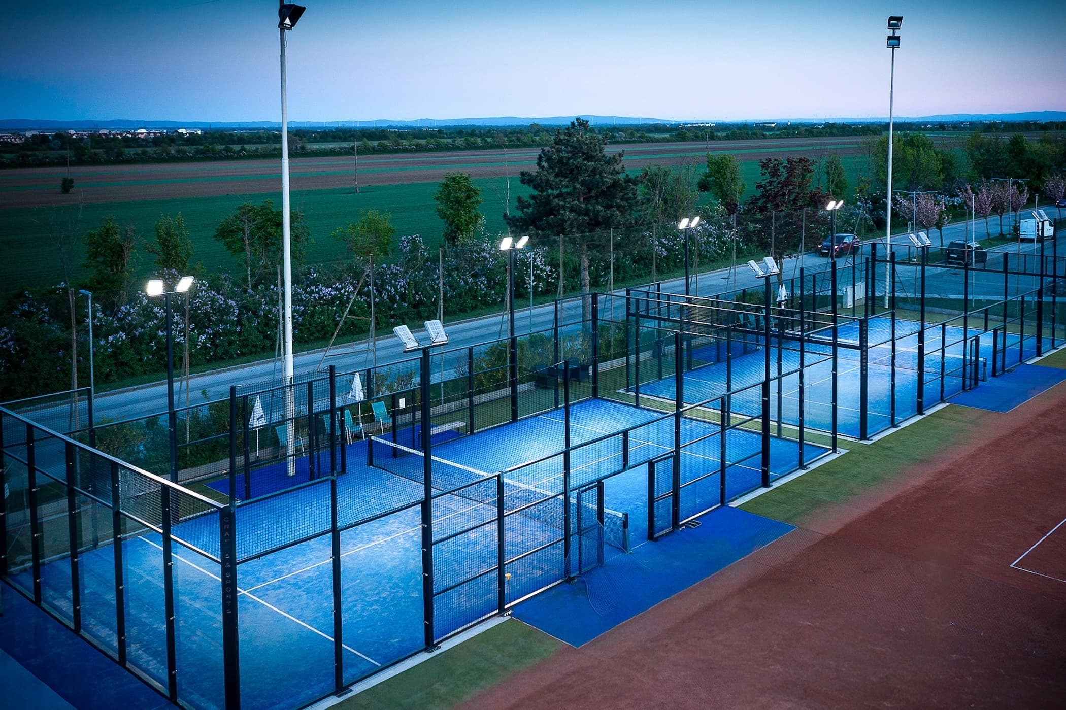 Zwei beleuchtete Outdoor-Padel-Courts bei Dämmerung bei Padel Vösendorf